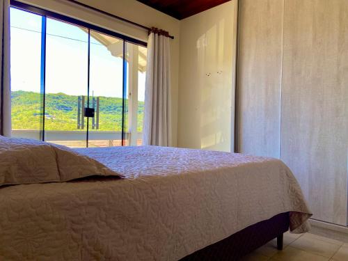 ein Schlafzimmer mit einem Bett und einem großen Fenster in der Unterkunft Refúgio Gramado: Seu Lar Temporário na Cidade dos Sonhos in Gramado