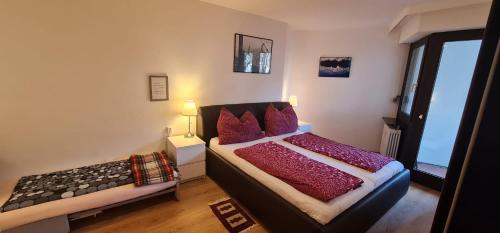 Un dormitorio con una cama con almohadas rojas y una ventana en Apartment Panorama, en Bad Reichenhall