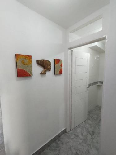 a hallway with three paintings on a wall at Parada Haus - Departamento en centro de San Juan in San Juan