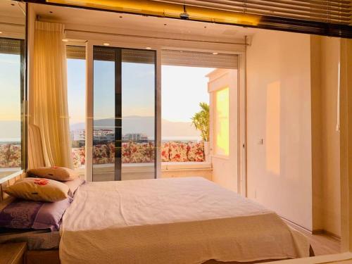 a bedroom with a large bed and a large window at Sea View Apartment with Veranda Beach Amazing in Vlorë