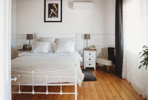 a white bedroom with a white bed and a chair at Hargreaves Cottage - close to CBD in Bendigo