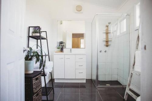 een witte badkamer met een wastafel en een douche bij Hargreaves Cottage - close to CBD in Bendigo