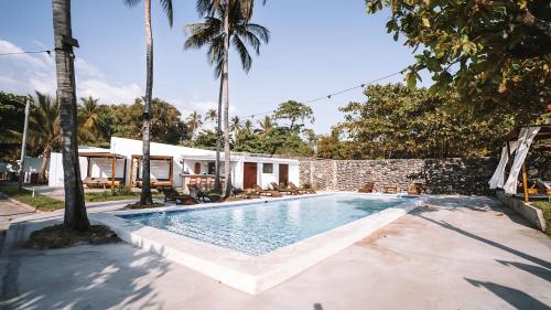 a swimming pool with palm trees and a house at Coco Surf Tropical Village in La Libertad