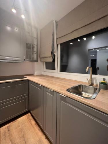 a kitchen with gray cabinets and a sink and a window at Boutique Serenity in Cluj-Napoca