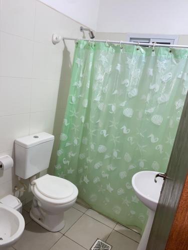 baño con aseo y cortina de ducha verde en Cabañas La Heredera en Salta