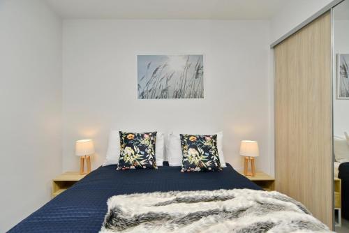 a bedroom with a blue bed with two lamps at Worcester Terrace One - Christchurch Holiday Homes in Christchurch