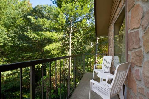 three white chairs sitting on a balcony with trees at Days Inn By Wyndham Pigeon Forge South in Pigeon Forge