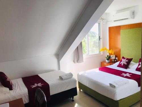 1 dormitorio con 2 camas y ventana en Alec's Hotel, en Apia