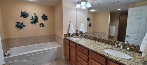 a bathroom with two sinks and a large mirror at Opus Condominiums in Daytona Beach Shores