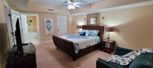 Opus Condominiums في Daytona Beach Shores: غرفة نوم بسرير وتلفزيون وأريكة