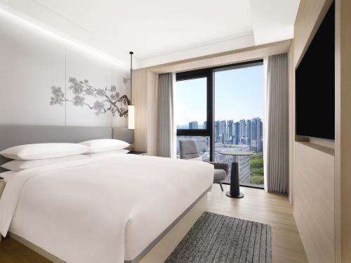 a bedroom with a large white bed and a large window at Courtyard by Marriott Sejong in Sejong