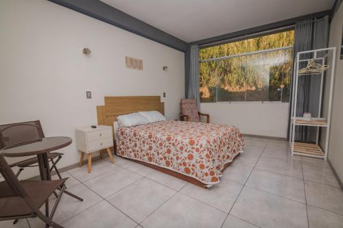 um quarto com uma cama, uma mesa e uma janela em HOSTAL MONTALVO VALLE em Moquegua