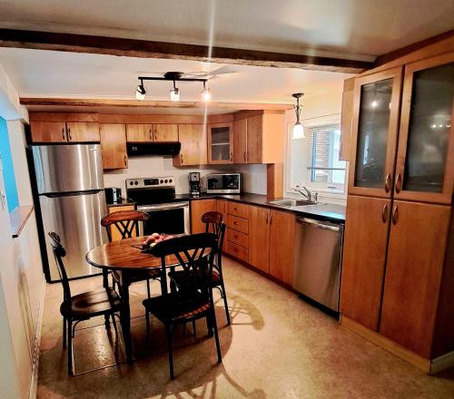 a kitchen with a table and chairs and a refrigerator at Gîte du Pionnier in L'islet Sur Mer