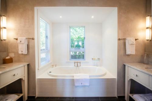 a white bathroom with a tub in a window at Pihopa Retreat in Nelson