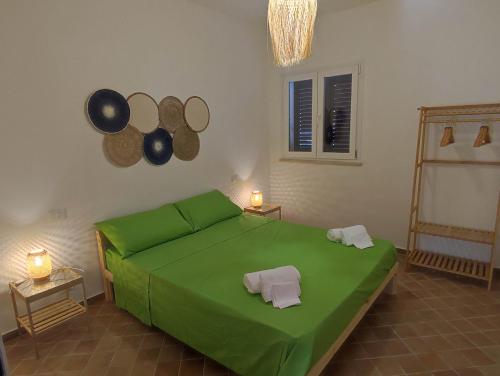 a green bed in a room with two mirrors at Casa Porto Palo in Porto Palo