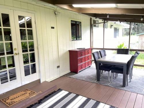 - une terrasse couverte avec une table et des chaises dans l'établissement THE MANONO HOUSE - Peaceful, Private 3Bd 2Bath Home near HILO, with AC!, à Keaau
