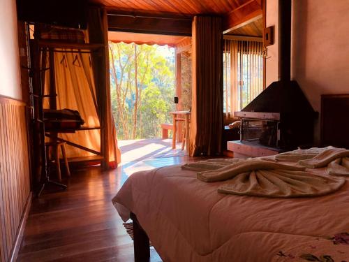 a bedroom with a bed and a large window at Pousada chalés Binitz in Visconde De Maua