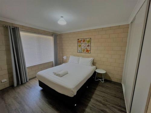 a bedroom with a large white bed and a window at Breakaway Esperance in Esperance