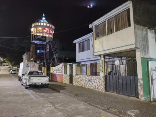 a street with a building with a clock tower at night at BAÑOS MINI DEPARTAMENTO AMOBLADO EN PLENO CENTRO de LA CIUDAD in Baños