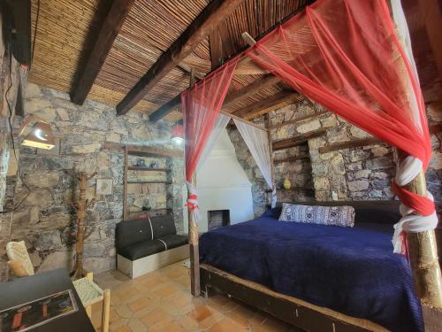 1 dormitorio con cama y pared de piedra en HOTEL RINCÓN MAGICO REAL DE CATORCE, en Real de Catorce