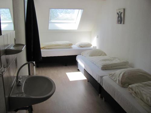 two beds in a room with a sink and a window at Appartementen Rijnhoeve in Koudekerk aan den Rijn