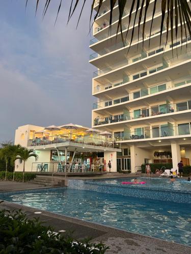 un hotel con piscina frente a un edificio en Resort Playa Azul Departamentos frente al mar, en Tonsupa