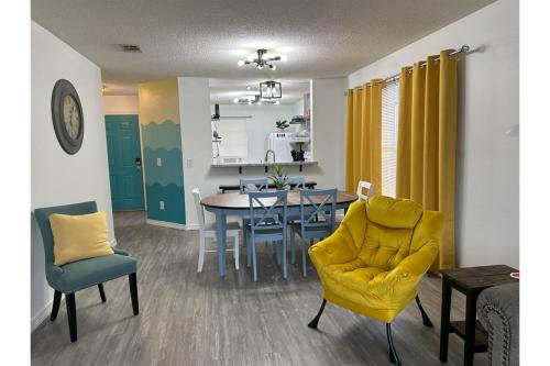 a living room with a dining room table and yellow chairs at Coral Sky in Pensacola