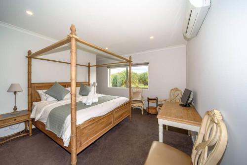 a bedroom with a wooden canopy bed and a desk at Family-Friendly Gorgeous Farm House (TF195223) in Dixons Creek