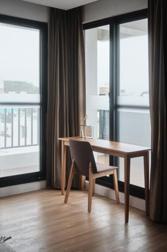 a desk and a chair in a room with windows at Here It's Home in Green Island