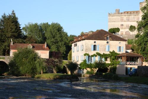 a house and a river with a castle in the background at Hostellerie Les Griffons in Brantome en Perigord