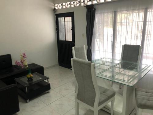a dining room with a glass table and chairs at Casa con calor de hogar con aire acondicionado in Neiva