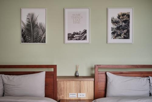 two beds in a bedroom with three pictures on the wall at Here It's Home in Green Island