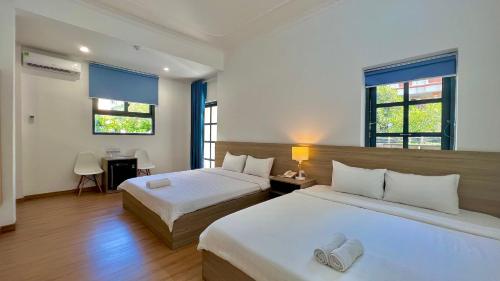 BAMBOO Hotel Vung Tau في فنغ تاو: غرفة نوم بسريرين و مكتب و نافذتين