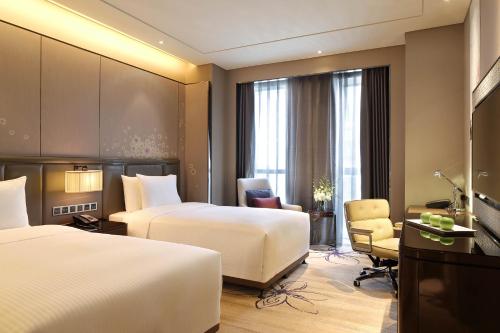 una habitación de hotel con 2 camas y una silla en Wanda Realm Guangyuan, en Guangyuan