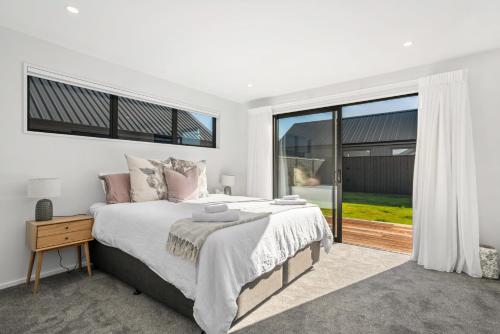 a bedroom with a large bed and a large window at Wooing Retreat - Cromwell Holiday Home in Cromwell