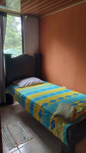 Una cama con un edredón colorido en un dormitorio en El Encanto Caño Negro en Caño Negro