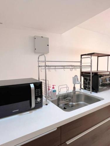 a kitchen with a sink and a microwave at Homely D'Sara @ Direct Link with MRT, Near Thomson Hospital & Sungai Buloh Hospital in Sungai Buluh