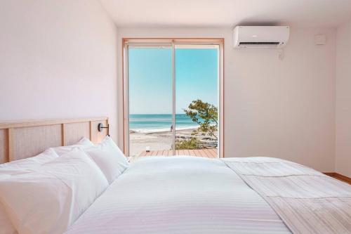 um quarto com uma cama e vista para a praia em VILLA KAWAZU - Umi - em Mitaka
