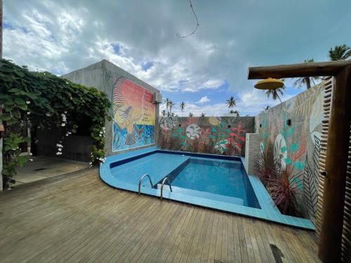a swimming pool in a yard with a mural at Chalé Palhano Beach in São Miguel dos Milagres