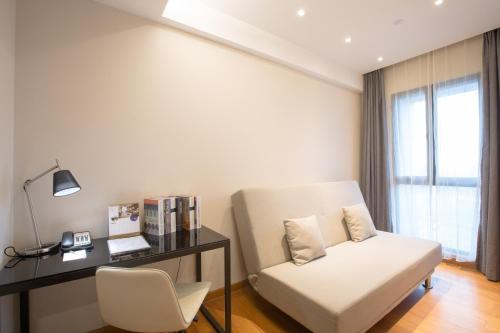 a living room with a white chair and a desk at Modena By Fraser New District Wuxi in Wuxi