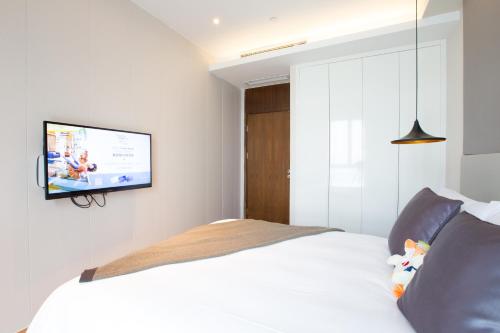 a bedroom with a bed with a flat screen tv on the wall at Modena By Fraser New District Wuxi in Wuxi