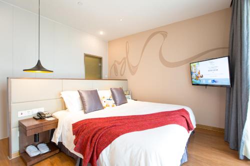 a bedroom with a bed and a flat screen tv at Modena By Fraser New District Wuxi in Wuxi