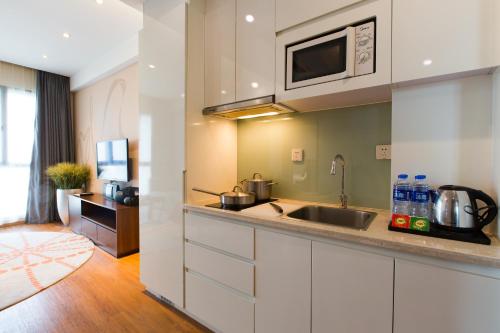 a kitchen with a sink and a microwave at Modena By Fraser New District Wuxi in Wuxi