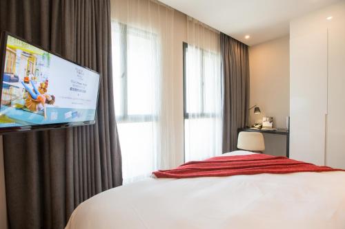 a hotel room with a bed and a flat screen tv at Modena By Fraser New District Wuxi in Wuxi