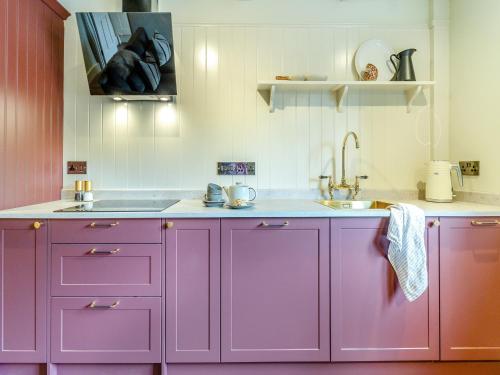 a kitchen with purple cabinets and a sink at Llygad Y Dydd - Uk42788 in Bow Street