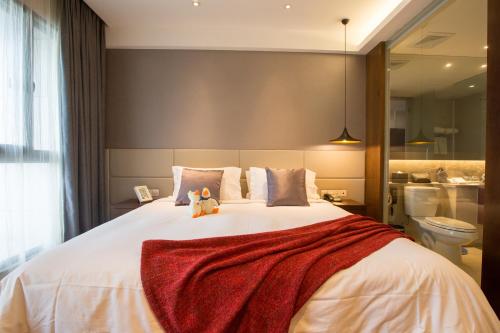 a large bed with two stuffed animals sitting on it at Modena By Fraser New District Wuxi in Wuxi