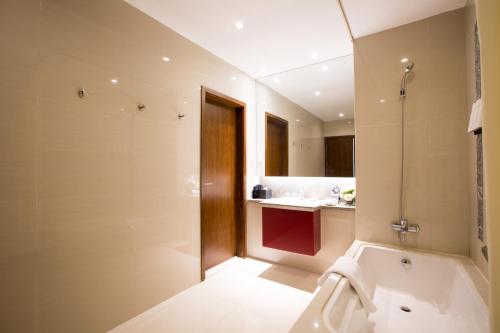 a bathroom with a bath tub and a sink at Modena By Fraser New District Wuxi in Wuxi