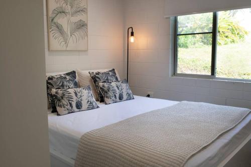 a bedroom with a bed with pillows and a window at Iona Mission Beach- Stroll to shops cafes & beach in Mission Beach