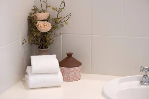 a bathroom with a sink and a vase with towels at Iona Mission Beach- Stroll to shops cafes & beach in Mission Beach