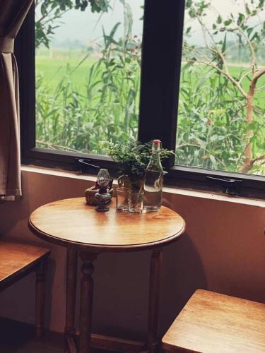 a small table with a bottle and a window at Nhà Lúa Homestay in Ninh Binh
